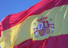 The national flag of Spain waving vividly against a clear blue sky in Cádiz, Andalucía.