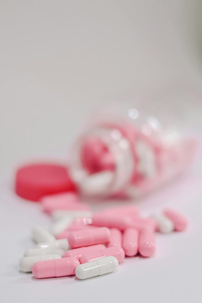 A focused shot of pink and white capsules spilling from an open bottle, highlighting medicinal use.